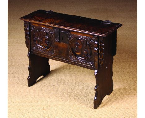 A Small & Rare Carved Oak Child's Coffer of boarded construction. The lid having a moulded edge on iron hinges. The front boa