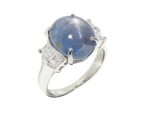 A star sapphire and diamond set ring claw set with an oval cabochon star sapphire, two baguette cut diamonds to each side, to