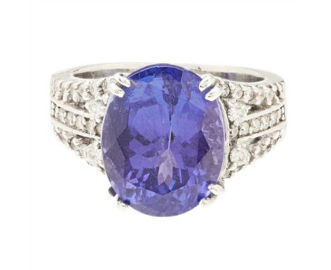 A 14ct white gold Tanzanite and diamond set cocktail ring claw set with an oval cut Tanzanite, the split shoulders and galler