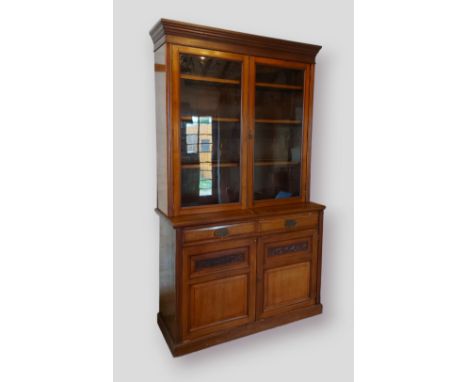 An Edwardian walnut bookcase by Maple &amp; Co, the moulded cornice above two glazed doors enclosing shelves, the lower secti