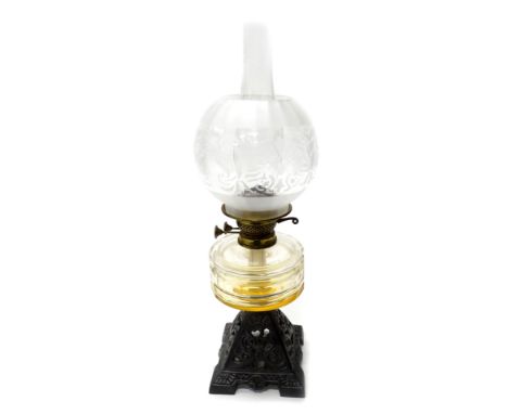 A Victorian cast iron oil lamp, with a clear glass reservoir and a part frosted shade, 60cm high overall.