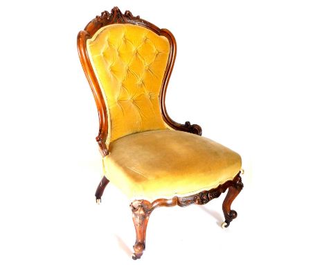 A Victorian walnut nursing chair, with a carved show frame, upholstered in buttoned gold velvet on cabriole legs with ceramic