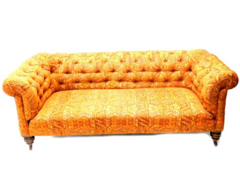 A Victorian mahogany Chesterfield sofa, reupholstered in geometric orange and multicoloured fabric, on turned legs with ceram