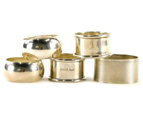 A collection of silver napkin rings, to include a pair of circular shaped pieces, and an oval napkin ring engraved with initi