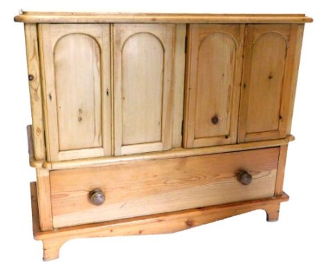 A pine side cabinet, the top with a moulded edge above two pairs of doors, each with arched panels enclosing a shelf, the bas