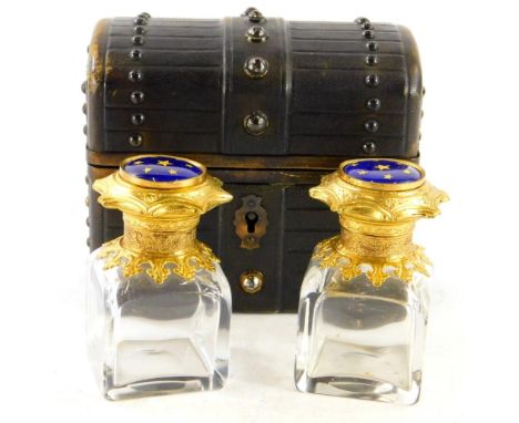 An early 20thC small box, made to simulate a trunk, containing two cut glass bottles with gilt and enamel lids set with stars