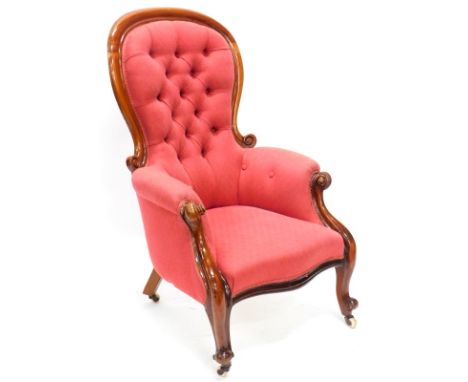 A Victorian mahogany show frame armchair, upholstered in red patterned fabric, with a button back, padded arms and seat, on c