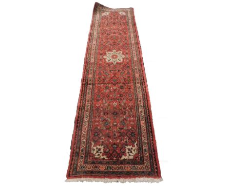 A Persian style runner, with an all over geometric design on a red ground, one wide and two narrow borders, 280cm x 75cm .