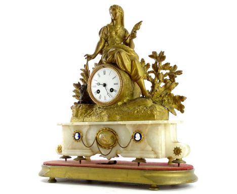 A late 19thC gilt metal mantel clock, the 8cm diameter Roman numeric dial surmounted by a figure of a lady flanked by trees, 