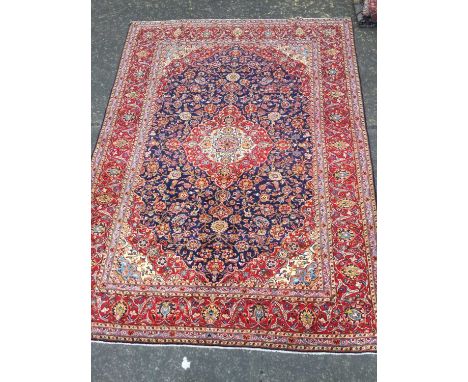 PERSIAN KASHAN HAND KNOTTED WOOL CARPET,with a central lozenge with floral designs, in a surround of floral designs on blue, 