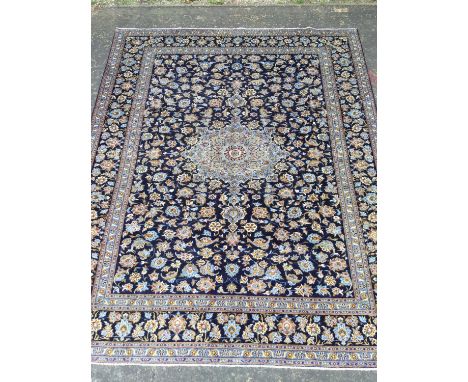 PERSIAN KASHAN HAND KNOTTED WOOL CARPET,with a central roundel of floral designs, surrounded by floral designs on a blue grou