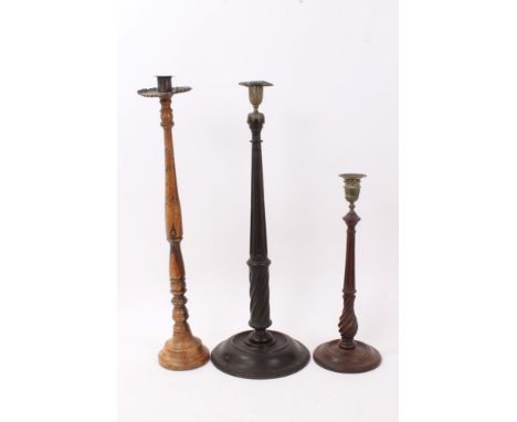 18th century lignum vitae candlestick, with brass sconce, 54cm high, together with two further 18th century turned treen cand