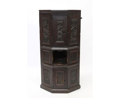 18th century carved pine standing corner cupboard, of canted form, with two carved tiers each enclosed by carved panel doors 