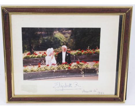 HM Queen Elizabeth The Queen Mother – signed photograph of Her Majesty with her page Reg Wilcox, in a garden setting, signed 