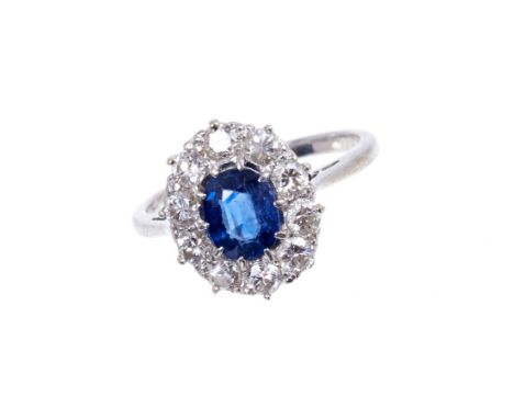 Sapphire and diamond cluster ring, the oval mixed cut blue sapphire surrounded by ten brilliant cut diamonds in platinum sett