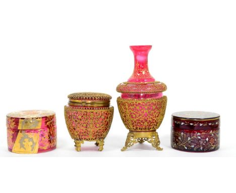 ~ A gilt and cranberry glass circular box, an enamel painted ruby glass circular box and two pieces of gilt metal mounted cra