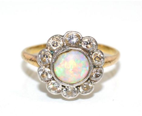 An opal and diamond cluster ring, a round cabochon opal within a border of milgrain set old cut diamonds, to knife edge shoul