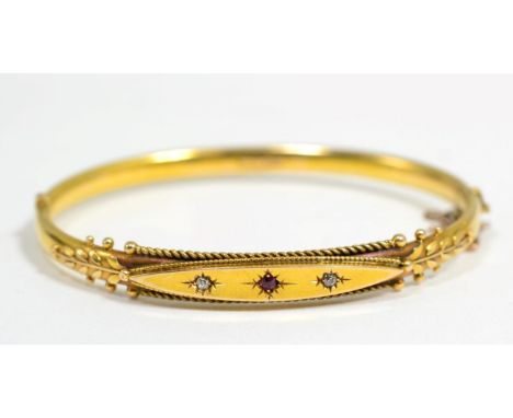 A Victorian ruby and diamond bangle, a star set round cut ruby spaced by old cut diamonds, to a beaded front and hinged back,