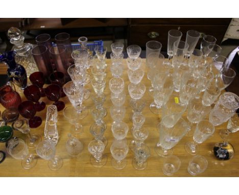 A quantity of various drinking glasses; a cranberry glass jug; a decanter and stopper etc.