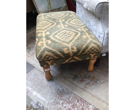An upholstered pouffe with turned legs. 