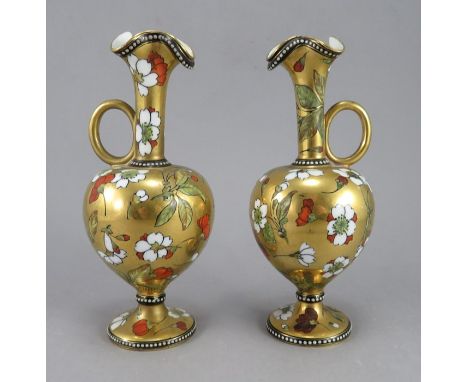 A pair of 19th Century Coalport ewers, flared openings, ring handles, jewelled borders containing a floral design on a gilt g