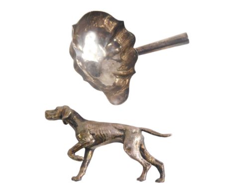 A white metal hunting dog, and part of a silver ladle.