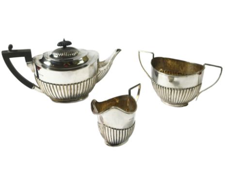 An Edwardian silver three piece tea set, with a teapot with ebonised handle and knop, each with part fluted decoration, Londo