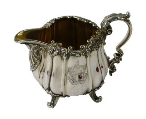 A George IV silver cream jug, cast overall with shells, scrolls and with a shaped handle with leaf cast thumb piece, gilt int