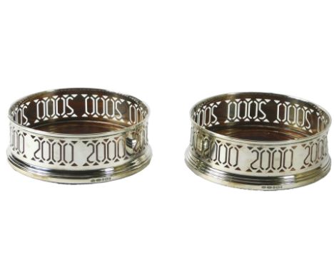 A pair of Elizabeth II silver coasters, produced for the Millennium 2000, with decoration to indicate this, on turned mahogan