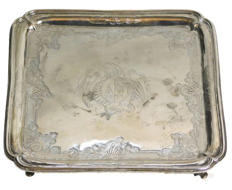 A George II silver square salver, engraved centrally with a crest and overall with an elaborate design of scrolls, shells, le