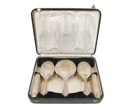 A George V silver mounted dressing table set, comprising mirror, two hand brushes and two clothes brushes, each with a centra