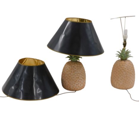 A pair of terracotta lamp bases, each modelled in the form of a pineapple, with brass mounts and black shades, 68cm high over