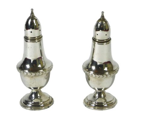 A pair of 19thC silver peppers, each with a leaf cast band, unmarked, 2oz, 12cm high.