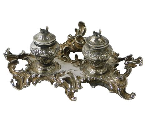 A 19thC French silver ink stand, cast overall with Rococo scrolls, with two hinged wells containing glass liners, left-hand l