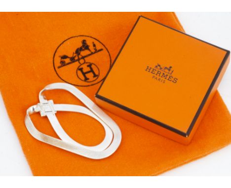 A white metal Hermes money clip, of bow design, marked Hermes, 6cm x 4cm in brown velvet case, orange box and cloth bag