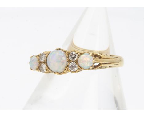 An 18ct gold opal and diamond dress ring, the three cabochon opals alternately set with pairs of brilliant cut diamonds on a 