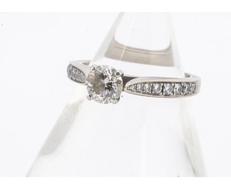 A GIA certificated diamond engagement ring, the brilliant cut in four claw setting with graduated diamond set shoulders all i