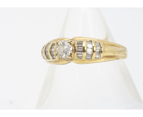 An 18ct gold diamond dress ring, the central round brilliant diamond in claw setting, with diamond set baguette cut shoulders