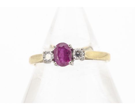 An 18ct gold ruby and diamond three stone ring, the white claw set mixed cut oval flanked by a pair of brilliant cut diamonds