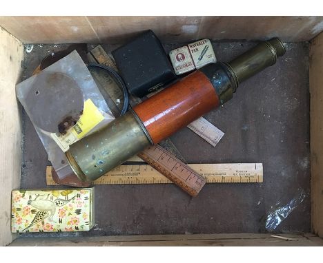 A pine chest containing various vintage rules and measures, lenses, a telescope, and an Aristo disc calculator