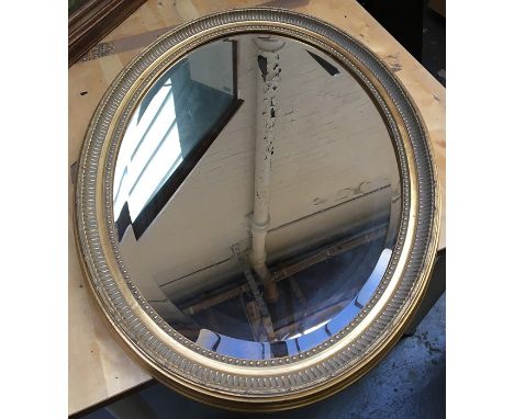 An oval gesso wall mirror with bevelled glass, 85cmH