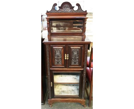 An Edwardian music cabinet with bevelled mirror and glass and decorative carving, raised on castors