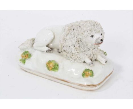A Staffordshire porcelain model of a recumbent poodle, circa 1830-40, picked out in enamels on a gilt-lined rectangular base,
