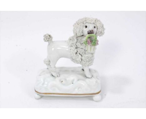 A Staffordshire porcelain model of a poodle, circa 1840, modelled standing with an enamelled basket of flowers in its mouth, 