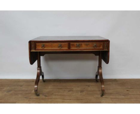 Good Regency rosewood and brass mounted sofa table, with rounded rectangular drop leaf top and two frieze drawers, each with 