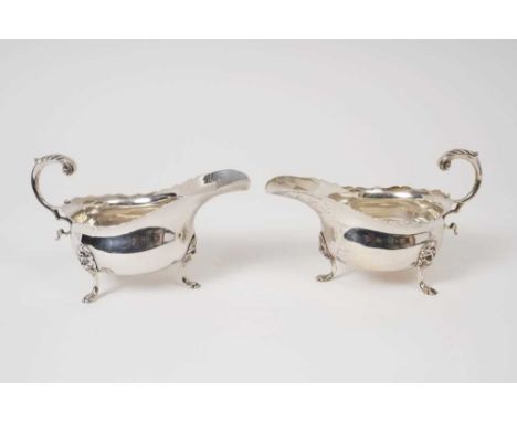 Pair Edwardian silver sauce boats of conventional form, with wavy borders and open scroll handles, on lion mask paw feet (Che