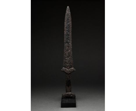 Circa 600-400 BC. An iron sword with long, broad tapering blade, which terminates in a point, rectangular grip with lobed low