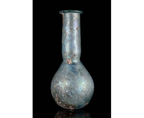 Circa 100 AD. A beautiful glass bottle with blue iridescence featuring a piriform body tapering to a long neck with flat fold