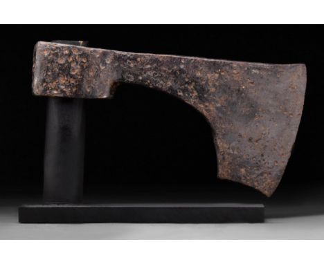 Circa 1000-900 AD A forged-iron axe head of a hefty form with a perforated socketing shaft, a dense neck, and a vertically or