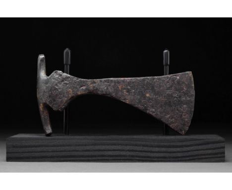Circa 1000-900 AD A forged-iron axe head of a hefty form with a perforated socketing shaft, a dense neck, and a vertically or